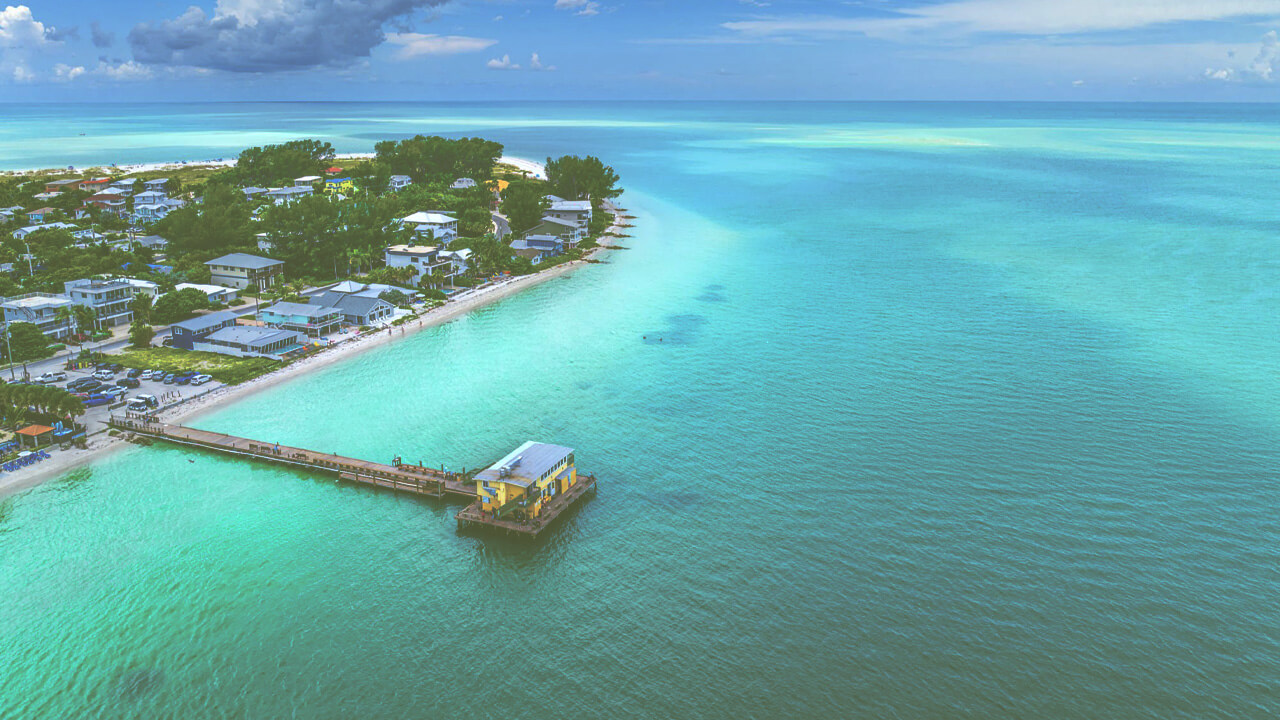aerial view of the one of the best beaches near Rye Ranch on the gulf coast of Florida - beautiful turquoise waters with a pier and boat dock on a sunny day