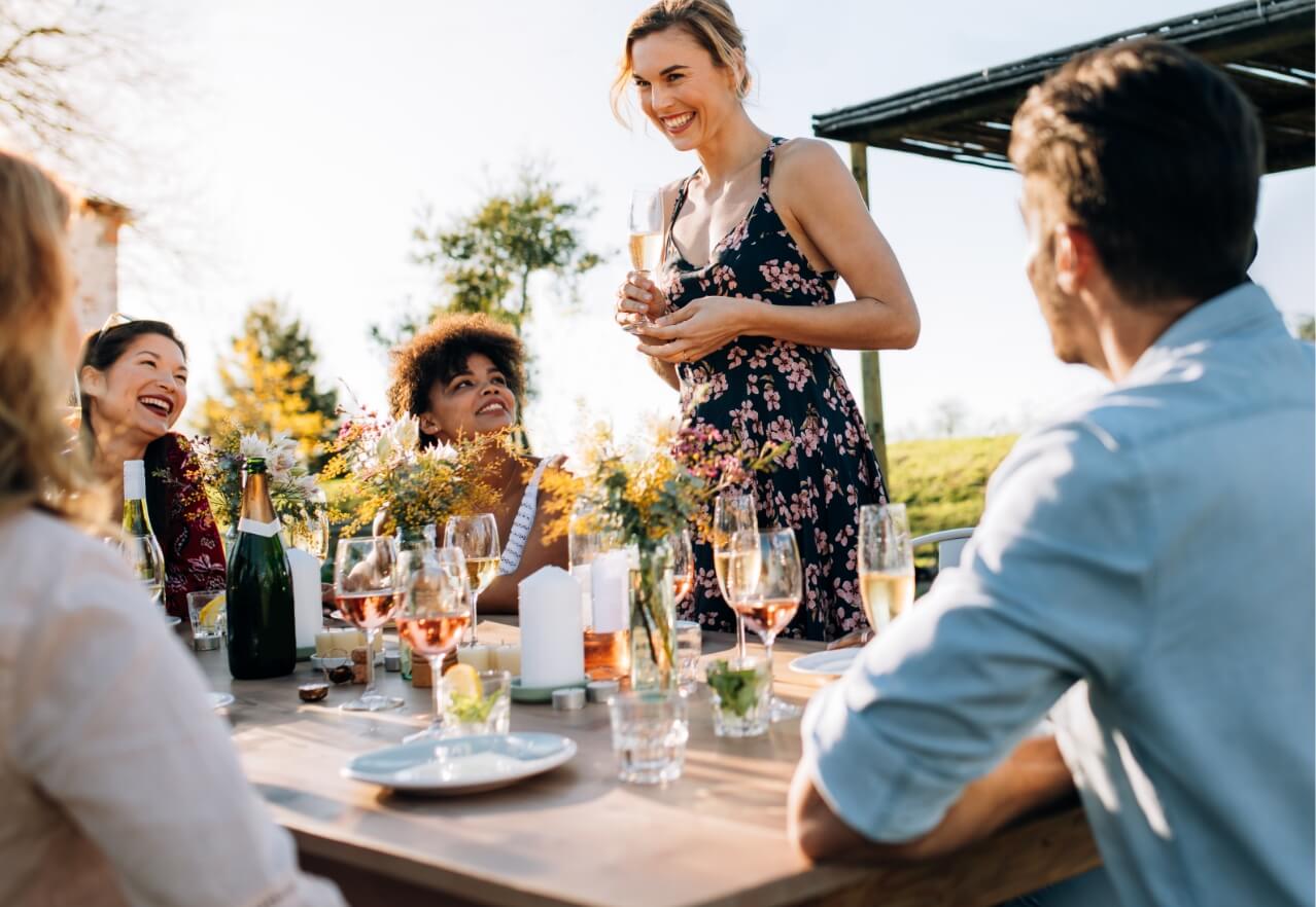 woman standing talking to a table over dinner outside