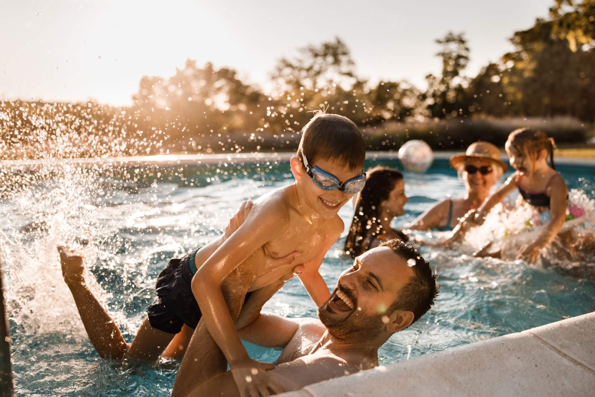 Playful father having fun with his small boy during family's summer day in the swimming pool.