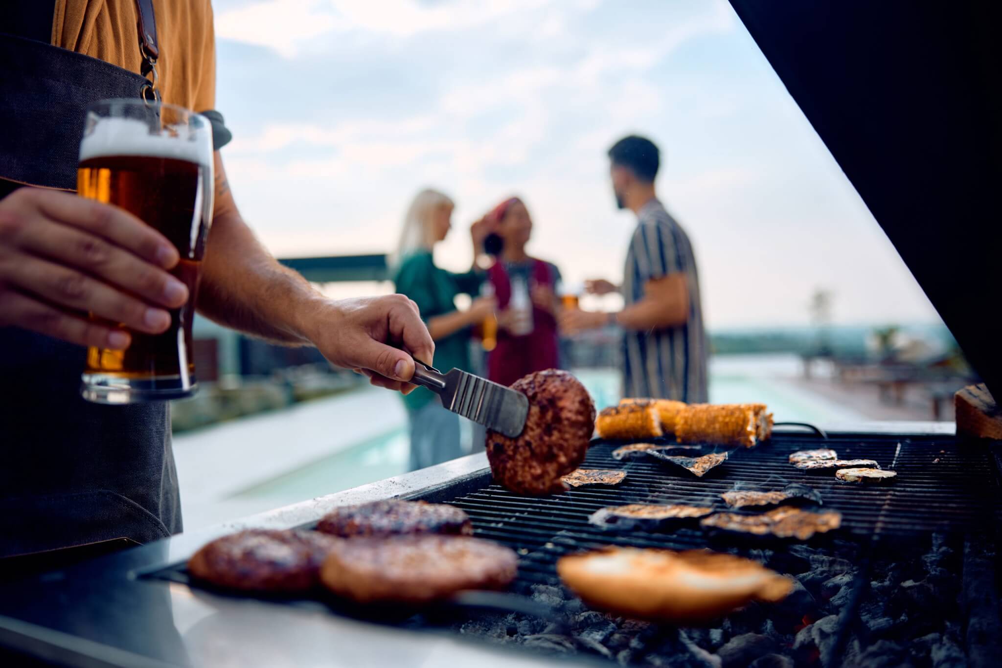 Close up of man grilling food on a barbecue on pool party.
