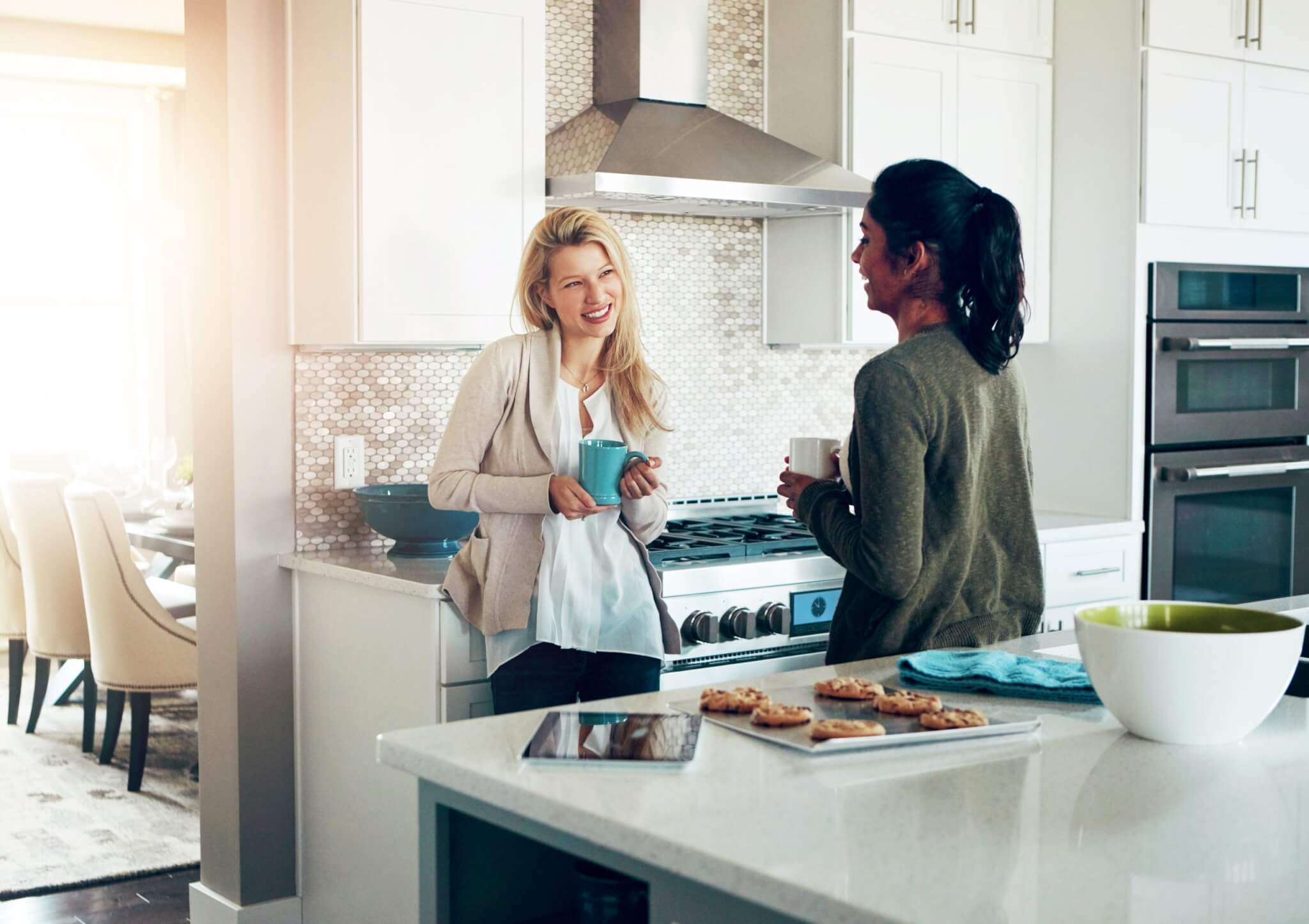 Talking, friends or women in kitchen for conversation, communication and weekend break together with beverage. Happy, girls and coffee cup in home for support, community and discussion with drink