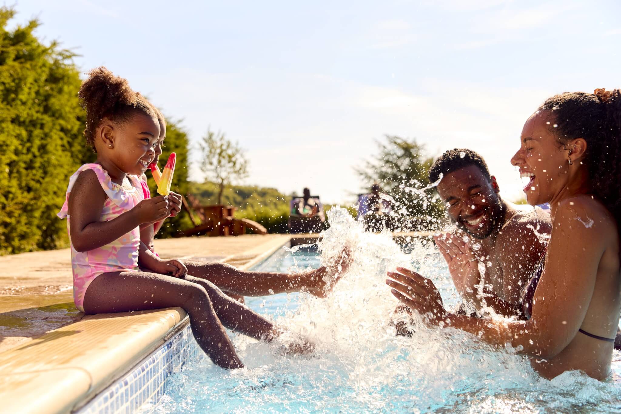 Family On Summer Holiday With Two Girls Eating Ice Lollies By Swimming Pool Splashing Parents - Life Here at Rye Ranch in Southwest Florida