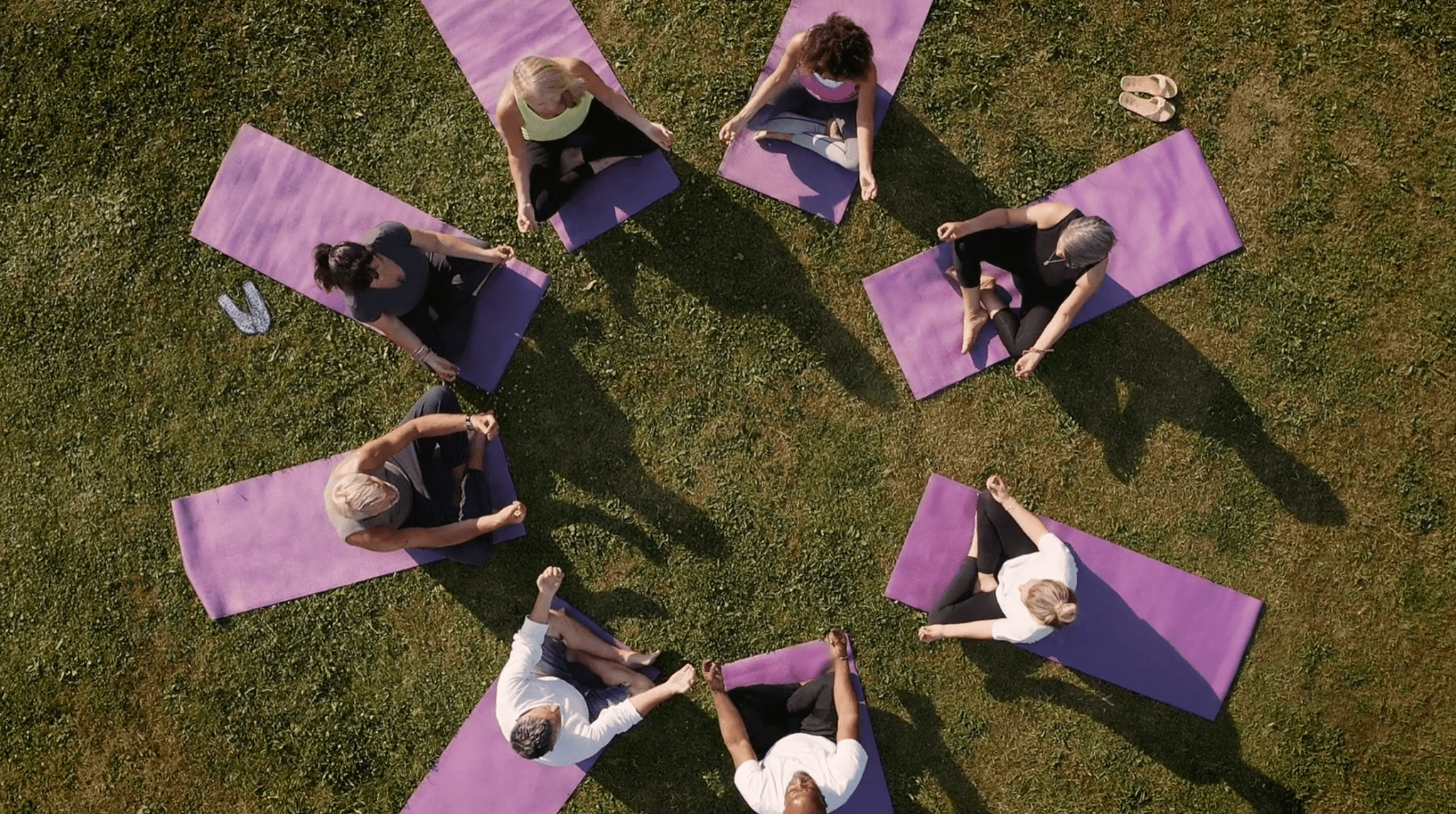 people in a circle doing yoga on grass