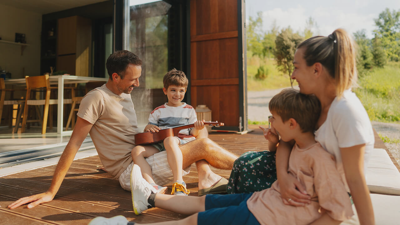 family-friendly home designs are enjoyed by a man, woman, and two young boys in front of an indoor-outdoor residential space